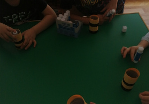Dzieci siedzą przy stole i wykonują pszczółkę z papieru